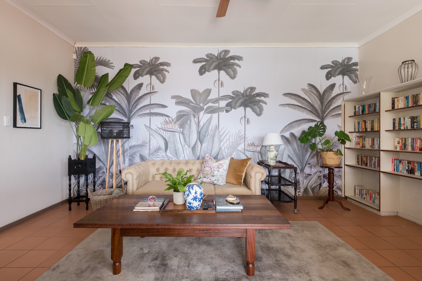 Library lounge with tropical mural, bookshelves and Chesterfield sofa at House Falcon Guest House